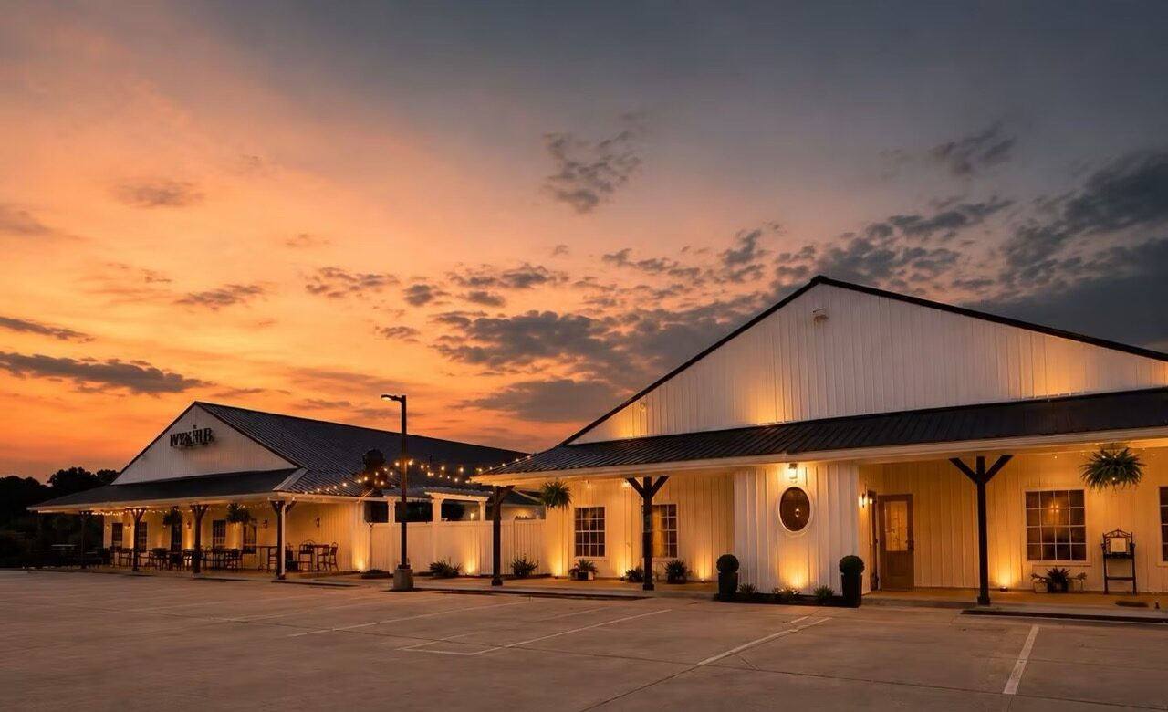 The Havenwing reception building and Marian Cocktails and Kitchen at sunset, lined with warm string lights.
